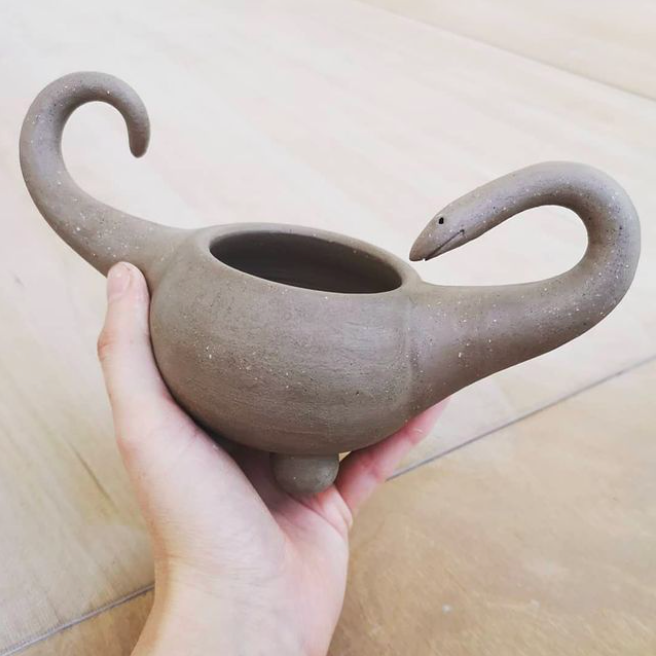 holding a work in progress ceramic dinosaur 